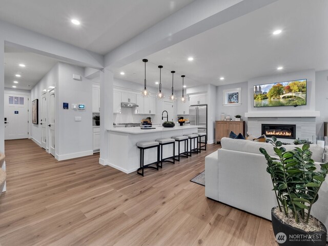 living room with a glass covered fireplace, recessed lighting, and light wood-type flooring