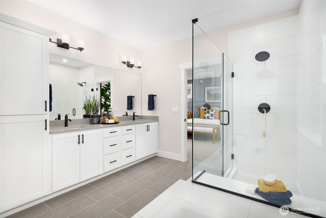 full bathroom with double vanity, tile patterned floors, a shower stall, and a sink