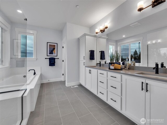 full bathroom with a garden tub, double vanity, tile patterned flooring, baseboards, and a sink