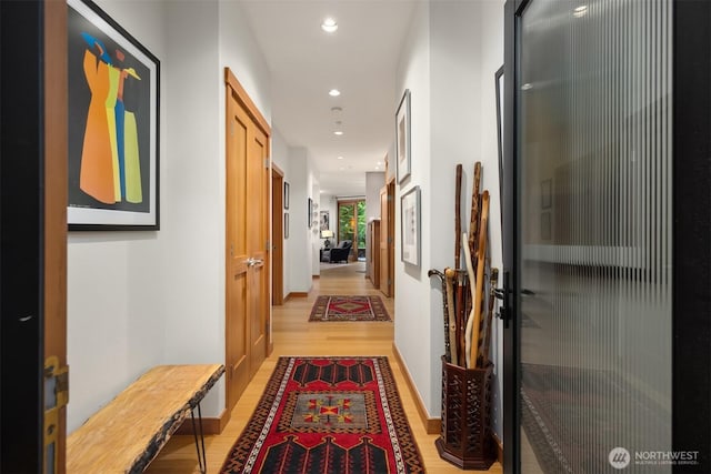 hallway featuring recessed lighting, light wood finished floors, and baseboards