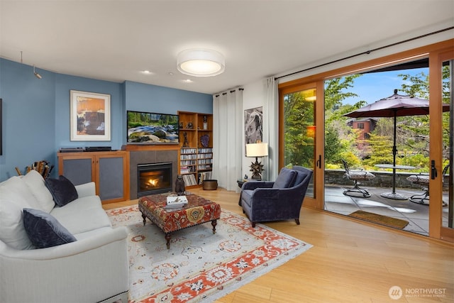 living room with a glass covered fireplace and wood finished floors