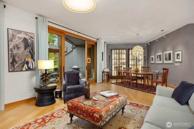 living area featuring baseboards, wood finished floors, and a notable chandelier