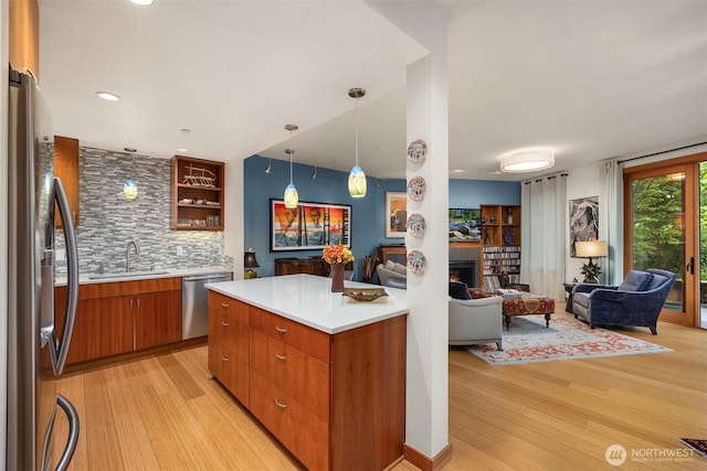 kitchen featuring open floor plan, appliances with stainless steel finishes, a sink, and light wood-style floors