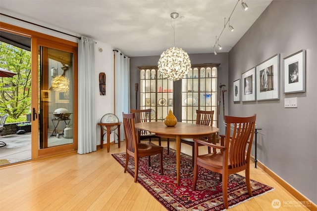 dining area featuring light wood-style floors, baseboards, a chandelier, and track lighting