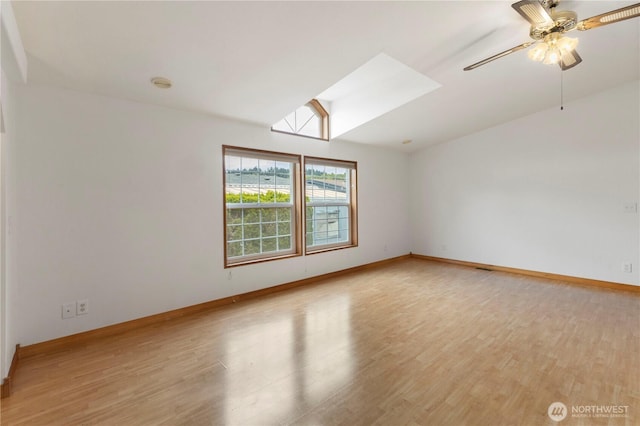 spare room with baseboards, a ceiling fan, a skylight, and light wood-style flooring