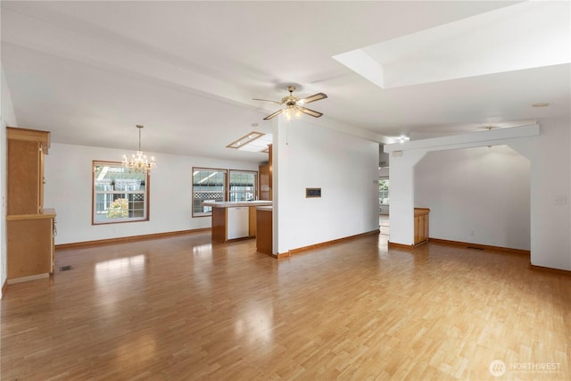 unfurnished living room with light wood-type flooring, arched walkways, baseboards, and ceiling fan with notable chandelier