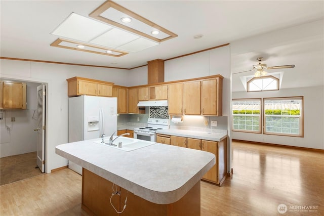 kitchen with white appliances, light countertops, under cabinet range hood, a sink, and light wood finished floors
