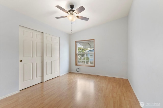 unfurnished bedroom featuring baseboards, ceiling fan, a closet, and light wood-style flooring
