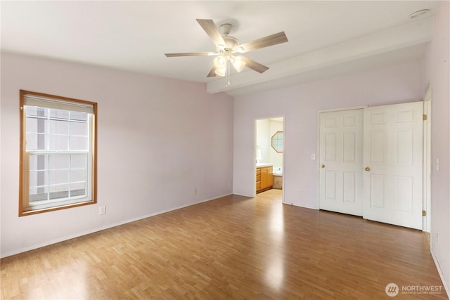 unfurnished bedroom with baseboards, ceiling fan, wood finished floors, and ensuite bath