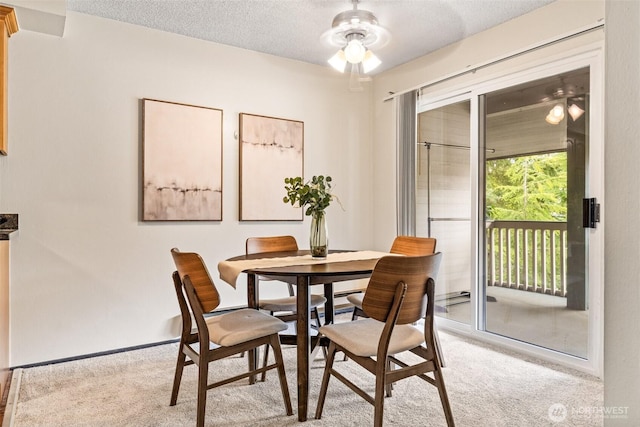 dining space featuring ceiling fan, light carpet, and a textured ceiling