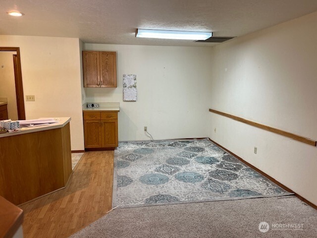 kitchen with brown cabinets, visible vents, light wood-style flooring, and light countertops