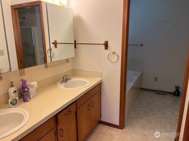 full bath featuring a sink, a shower with shower door, and double vanity