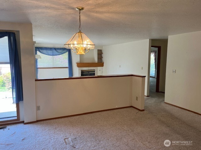 empty room with baseboards, a textured ceiling, carpet, and a notable chandelier