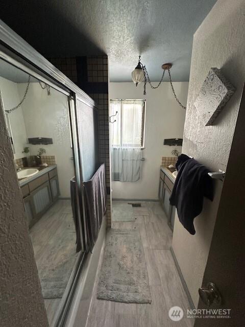 2232 177th Pl SW, Lynnwood, WA 98037 - bathroom featuring a shower stall, vanity, a textured ceiling, and wood finished floors