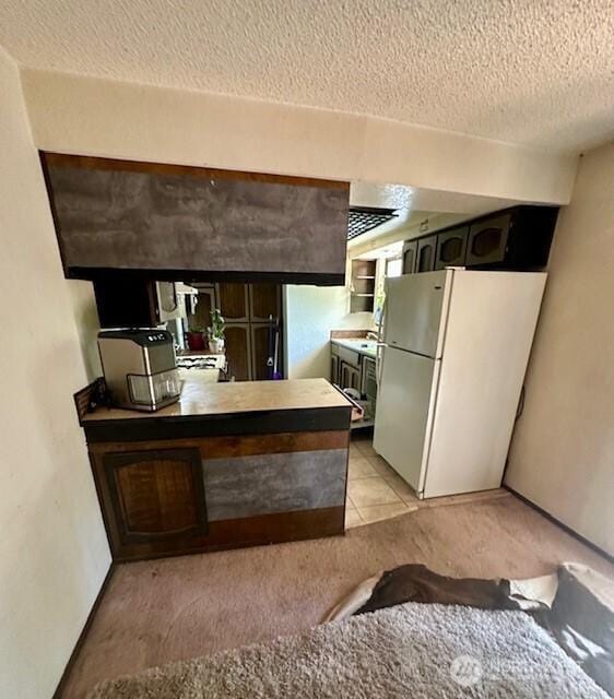 2232 177th Pl SW, Lynnwood, WA 98037 - kitchen featuring freestanding refrigerator, a textured ceiling, a sink, a peninsula, and light carpet