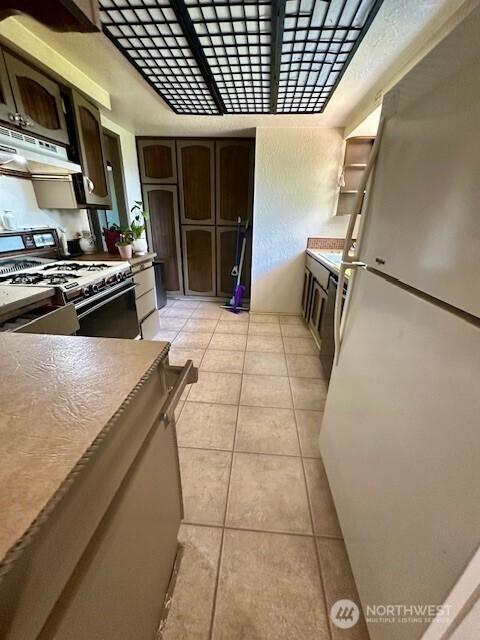 2232 177th Pl SW, Lynnwood, WA 98037 - kitchen with under cabinet range hood, dark brown cabinets, white appliances, and light tile patterned floors