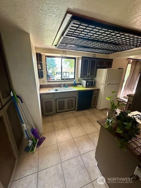 2232 177th Pl SW, Lynnwood, WA 98037 - kitchen featuring a textured ceiling, stainless steel microwave, light tile patterned flooring, and a sink
