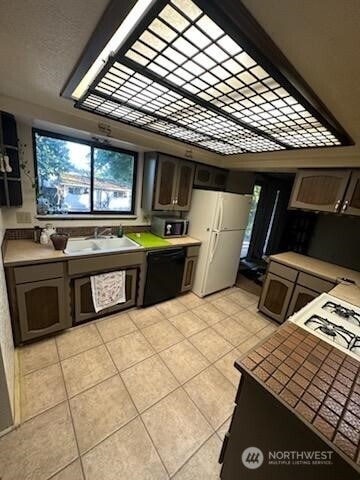2232 177th Pl SW, Lynnwood, WA 98037 - kitchen with light tile patterned floors, a sink, freestanding refrigerator, black dishwasher, and light countertops