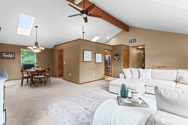 living room featuring light carpet, ceiling fan with notable chandelier, baseboards, visible vents, and lofted ceiling with skylight