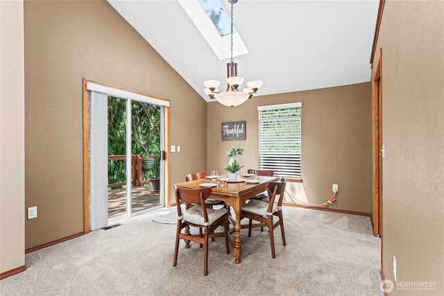 dining room featuring an inviting chandelier, plenty of natural light, vaulted ceiling with skylight, and light colored carpet