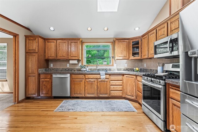 kitchen with a sink, backsplash, brown cabinets, and stainless steel appliances