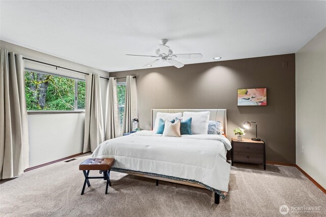 carpeted bedroom featuring baseboards, a ceiling fan, and visible vents
