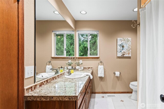 bathroom with baseboards, vanity, toilet, and visible vents