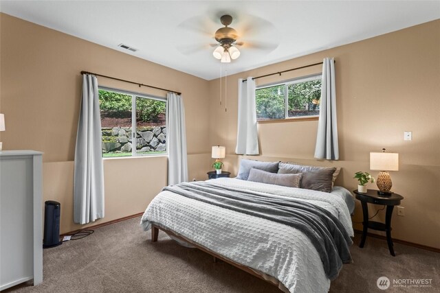 carpeted bedroom with a ceiling fan, baseboards, visible vents, and multiple windows