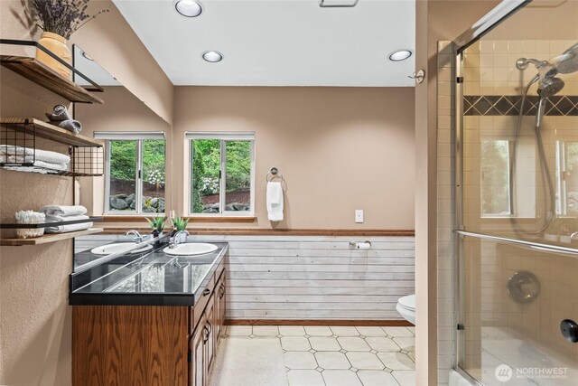 full bath featuring vanity, a shower with door, wainscoting, toilet, and recessed lighting