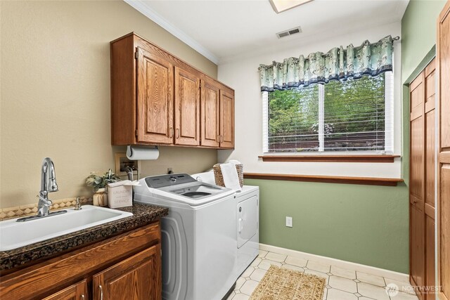 washroom with cabinet space, crown molding, a sink, separate washer and dryer, and visible vents