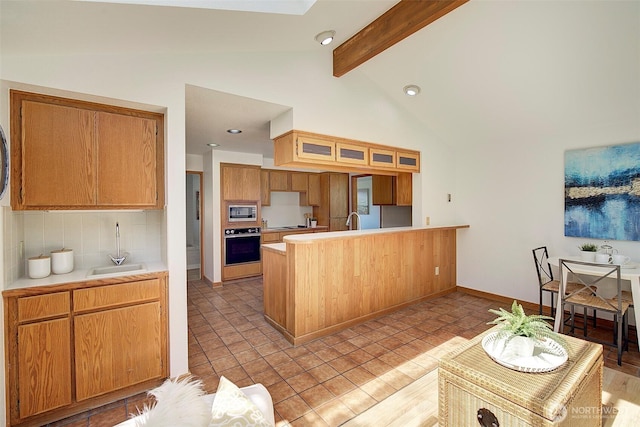 kitchen with a sink, beam ceiling, black oven, a peninsula, and stainless steel microwave