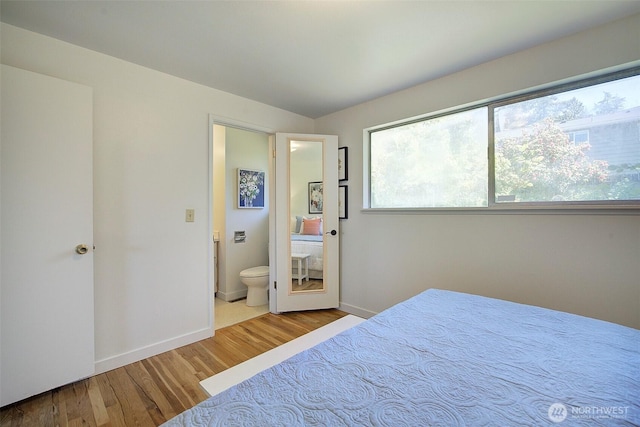 bedroom with baseboards, wood finished floors, and connected bathroom