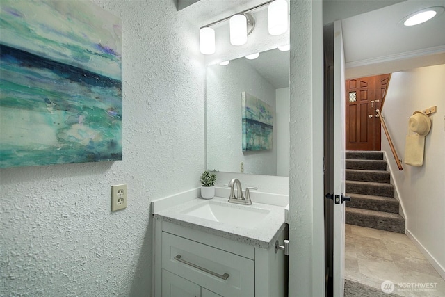 bathroom featuring a textured wall, baseboards, and vanity