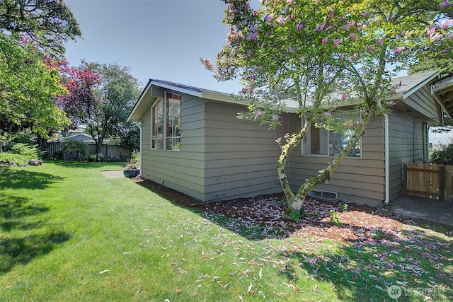 view of home's exterior featuring a lawn and fence