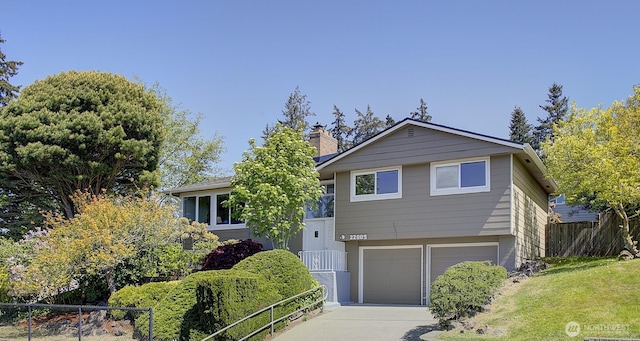 view of front facade featuring fence, a chimney, driveway, and a garage