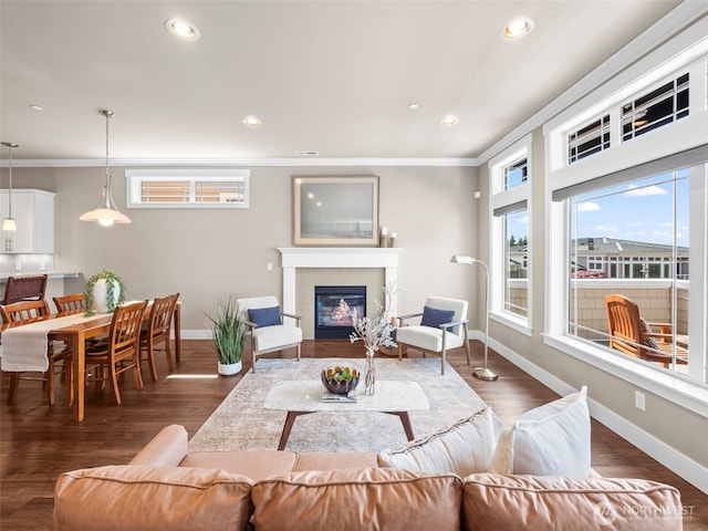 living room featuring baseboards, ornamental molding, and a tile fireplace