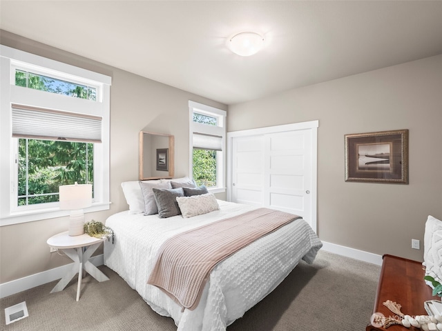 bedroom featuring visible vents, baseboards, a closet, and light carpet