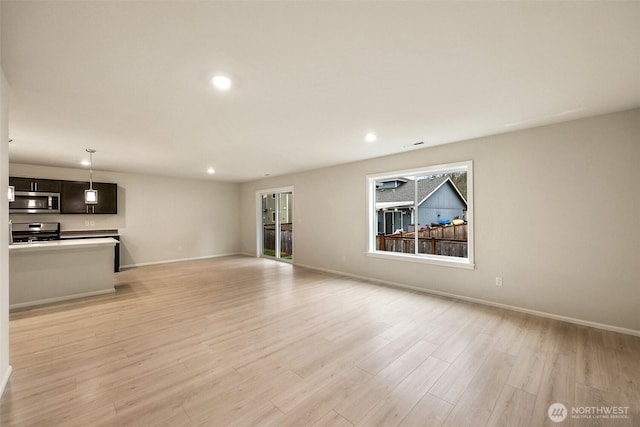 unfurnished living room featuring recessed lighting, baseboards, and light wood-style floors