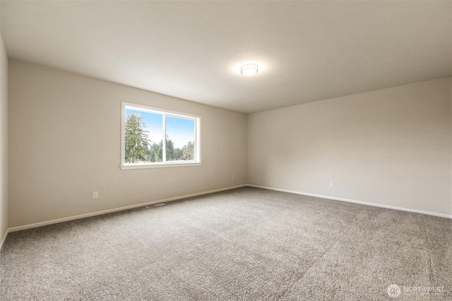 spare room with carpet floors, baseboards, and visible vents