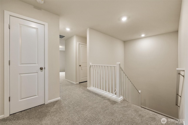 hallway with visible vents, baseboards, an upstairs landing, carpet flooring, and recessed lighting