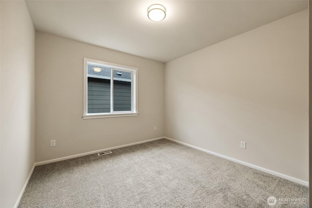 spare room featuring baseboards, visible vents, and carpet