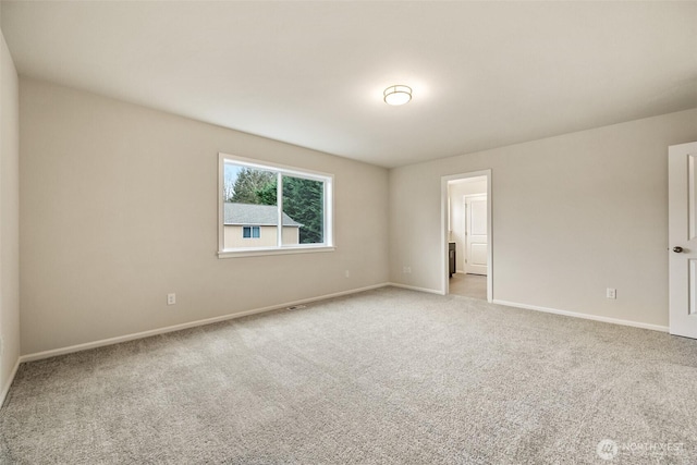 spare room with baseboards and light carpet