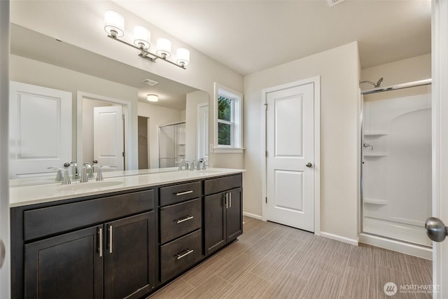 bathroom featuring a sink, double vanity, baseboards, a shower stall, and visible vents