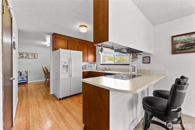 109 Lime St, Omak, WA 98841 - kitchen with a breakfast bar, white appliances, light countertops, a textured ceiling, and a peninsula