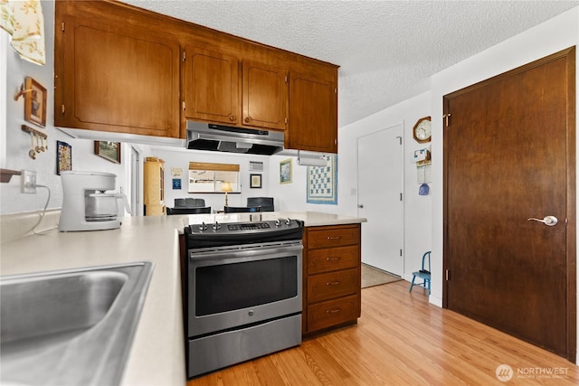 109 Lime St, Omak, WA 98841 - kitchen featuring stainless steel range with electric stovetop, light countertops, under cabinet range hood, a sink, and light wood finished floors