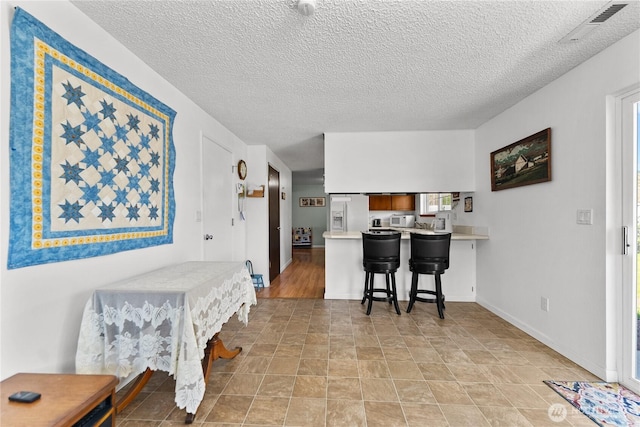 109 Lime St, Omak, WA 98841 - dining room featuring visible vents, a textured ceiling, baseboards, and stone finish floor
