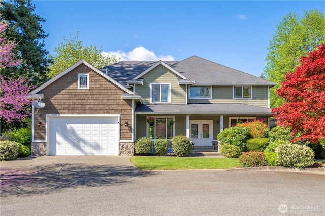 craftsman inspired home with an attached garage, stone siding, aphalt driveway, a porch, and french doors