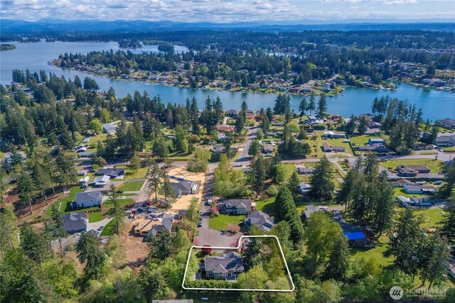 drone / aerial view with a residential view, a water view, and a wooded view
