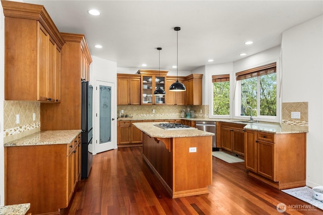 kitchen with appliances with stainless steel finishes, brown cabinetry, backsplash, and a center island