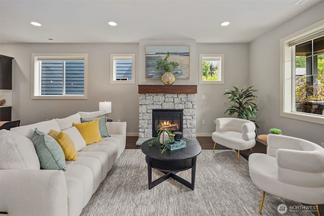 living room featuring baseboards, a fireplace, recessed lighting, and wood finished floors